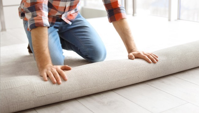 Man rolling carpet for installation | Karen's Advance Floors